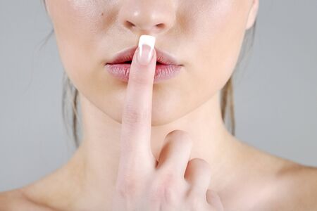 Young woman in a beauty style pose with a finger over her mouthの写真素材
