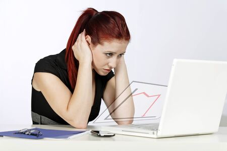 Young woman at her desk displaying a concept of loss and declineの写真素材