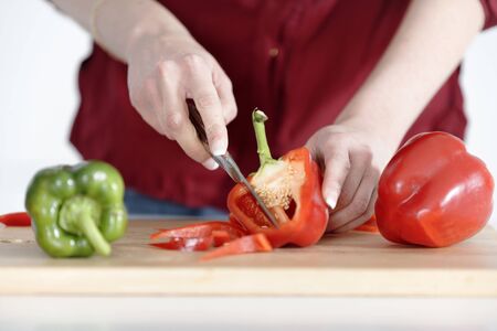 Woman's hands slicing red and green peppers on a chopping boardの写真素材