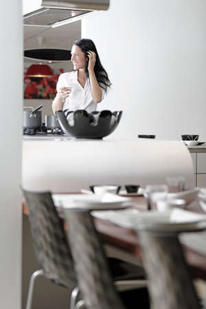 Beautiful young woman relaxing in her elegant white kitchenの写真素材