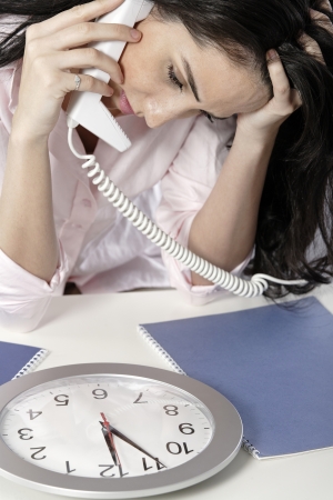 Woman on the phone watching a clock with a deadline approachingの写真素材
