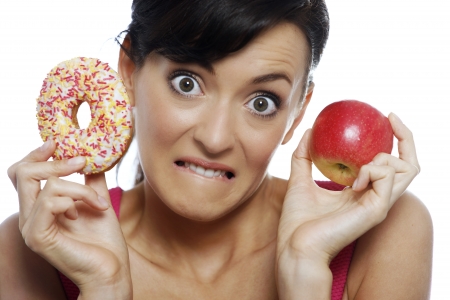 Young woman deciding between an apple or doughnut.の写真素材