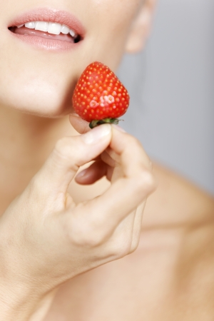 Young woman holding a strawberry in a beauty style pose.の写真素材