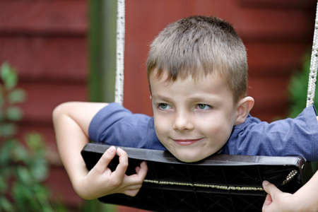 Young boy having fun outside on a swingの写真素材