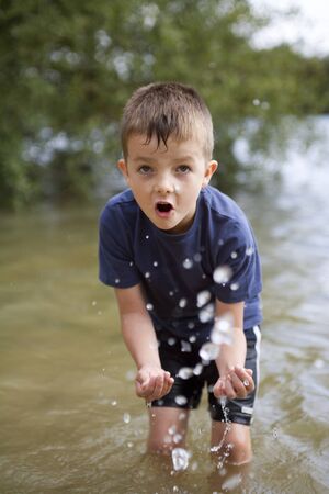 Young boy playing in the river splashing and exploringの写真素材