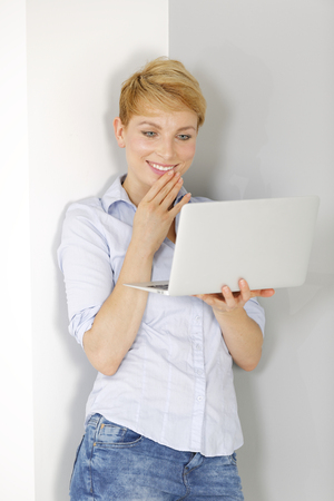 Attractive young woman using her laptop computer smilingの写真素材