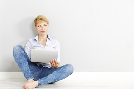 Attractive young woman using her laptop computer sitting on the floorの写真素材