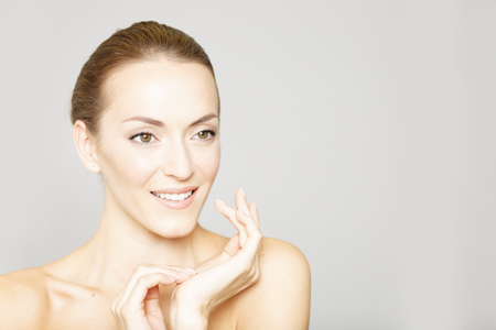 Beautiful young womans face with her hand resting on her chin and neck in a beauty style poseの写真素材