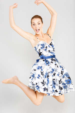 Beautiful young woman in a flowing blue summer dress dancing and jumpingの写真素材