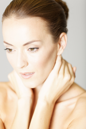 Beautiful young womans face with her hand resting on her chin and neck in a beauty style poseの写真素材