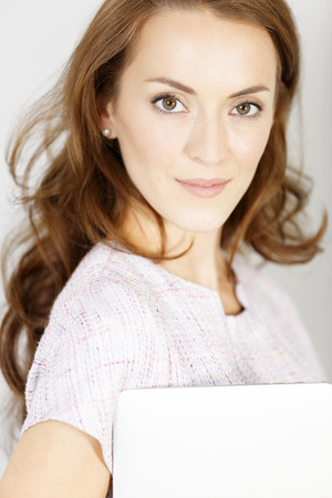 Young woman holding a closed laptop waiting for an appointment in a smart purple dressの写真素材
