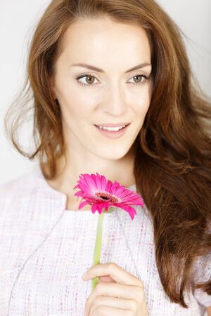 Romantic looking woman holding a fresh red flower smilingの写真素材