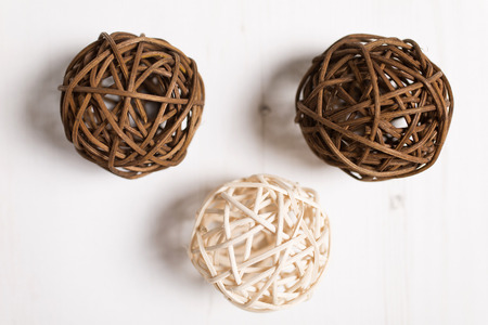 Three wicker balls together on a light wood surfaceの写真素材