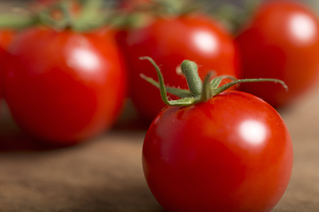 Beautiful fresh cherry tomatoes on a wooden kitchen work surfaceの写真素材
