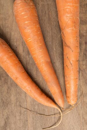 Selection of fresh raw carrots on a wooden kitchen work surface