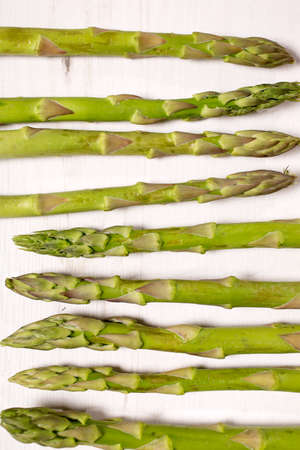 fresh raw asparagus on a light wooden kitchen work surfaceの写真素材