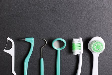 Selection of dentist brushes and tools on a black slate surfaceの写真素材