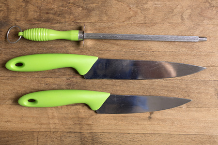 Stylish collection of modern kitchen knives and a sharpener on a wooden work surfaceの写真素材