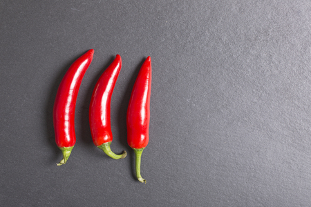 Fresh red chilli on black slate with copy spaceの写真素材