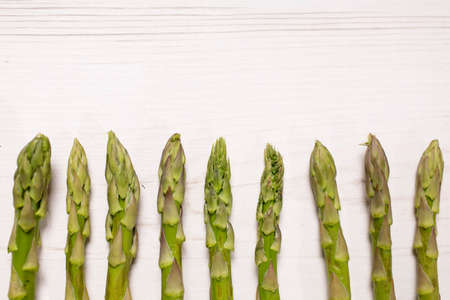 fresh raw asparagus on a light wooden kitchen work surfaceの写真素材