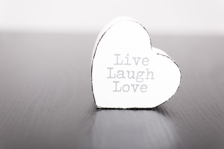 Single white wooden heart with the slogan live laugh love on the frontの写真素材