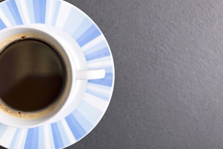 Freash coffee in a cup and saucer on a black slate work surfaceの写真素材