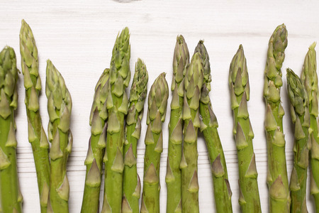 fresh raw asparagus on a light wooden kitchen work surfaceの写真素材