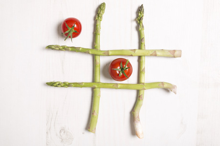 fresh raw asparagus laid out like naughts and crosses game using tomatoesの写真素材