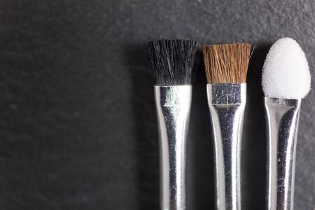 Stylish make up brushes on a black slate surface of all sizes