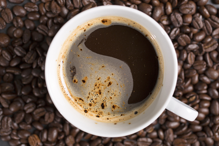 Still life of fresh roasted coffee beans with a white mug on a black slate surfaceの写真素材