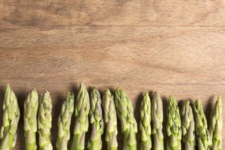 Fresh raw asparagus on a wooden kitchen work surfaceの写真素材