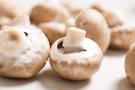 Fresh selection of chestnut mushrooms on a light wooden kitchen surfaceの写真素材