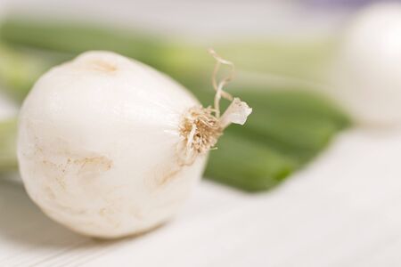 Large spring onion bulbs on a light wooden surfaceの写真素材
