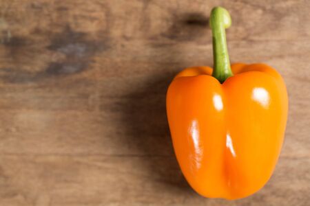 Fresh raw orange pepper on wooden kitchen work surfaceの写真素材