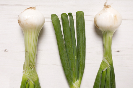 Large spring onion bulbs on a light wooden surfaceの写真素材