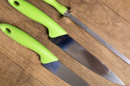 Stylish collection of modern kitchen knives and a sharpener on a wooden work surfaceの写真素材