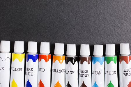 Selection of coloured paint tubes on a black slate surfaceの写真素材