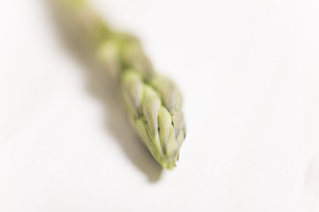 Detail of fresh raw asparagus on a light wooden kitchen work surfaceの写真素材