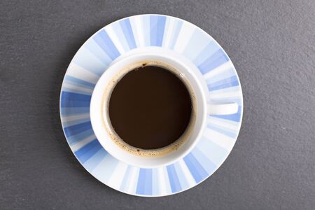 Freash coffee in a cup and saucer on a black slate work surfaceの写真素材