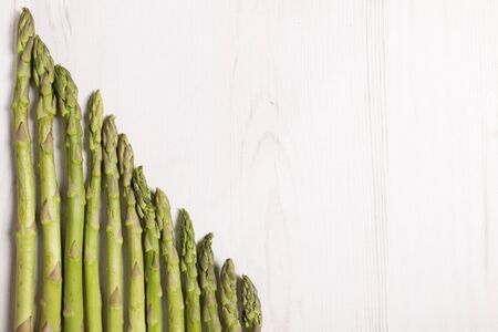 fresh raw asparagus on a light wooden kitchen work surfaceの写真素材