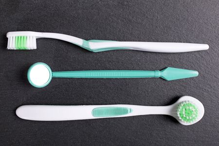 Selection of dentist brushes and tools on a black slate surface