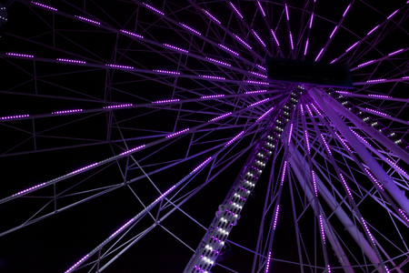 Violet ferris wheel illuminated at nightの写真素材