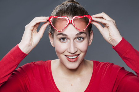 lovely 20s woman laughing and looking over her fun red glassesの写真素材