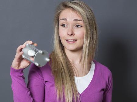 playful young blond woman holding hourglass for concept of time managementの写真素材