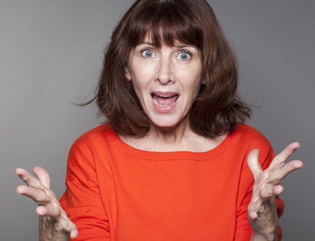 portrait of energetic beautiful 50's woman with both fists held strong for success and stimulationの写真素材