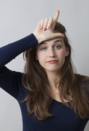 stunned woman making the L sign on forehead for loser message, cool hand gesture for youth cultureの写真素材