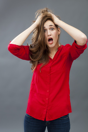 surprise and disappointment concept - portrait of a disturbed 20's woman messing up her hair expressing confusion,studio shotの写真素材