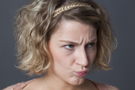 closeup portrait of cute 20s girl frowning, disappointed and angry at something or someoneの写真素材