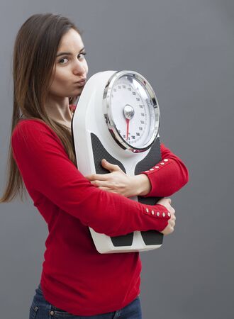 focused 20s girl in love with her weighting scale for wellness and weight controlの写真素材