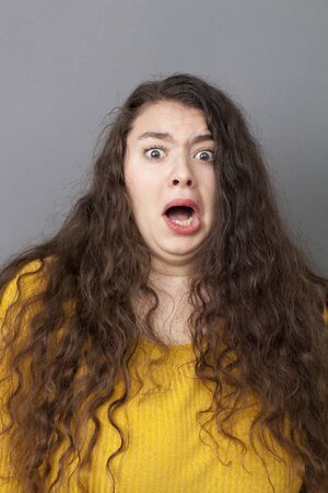 fear concept - young fat woman with long brown hair looking terrified and stressed out with eyes wide opened, studio shotの写真素材